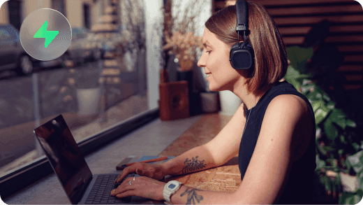 A musician wearing headphones while working on a laptop