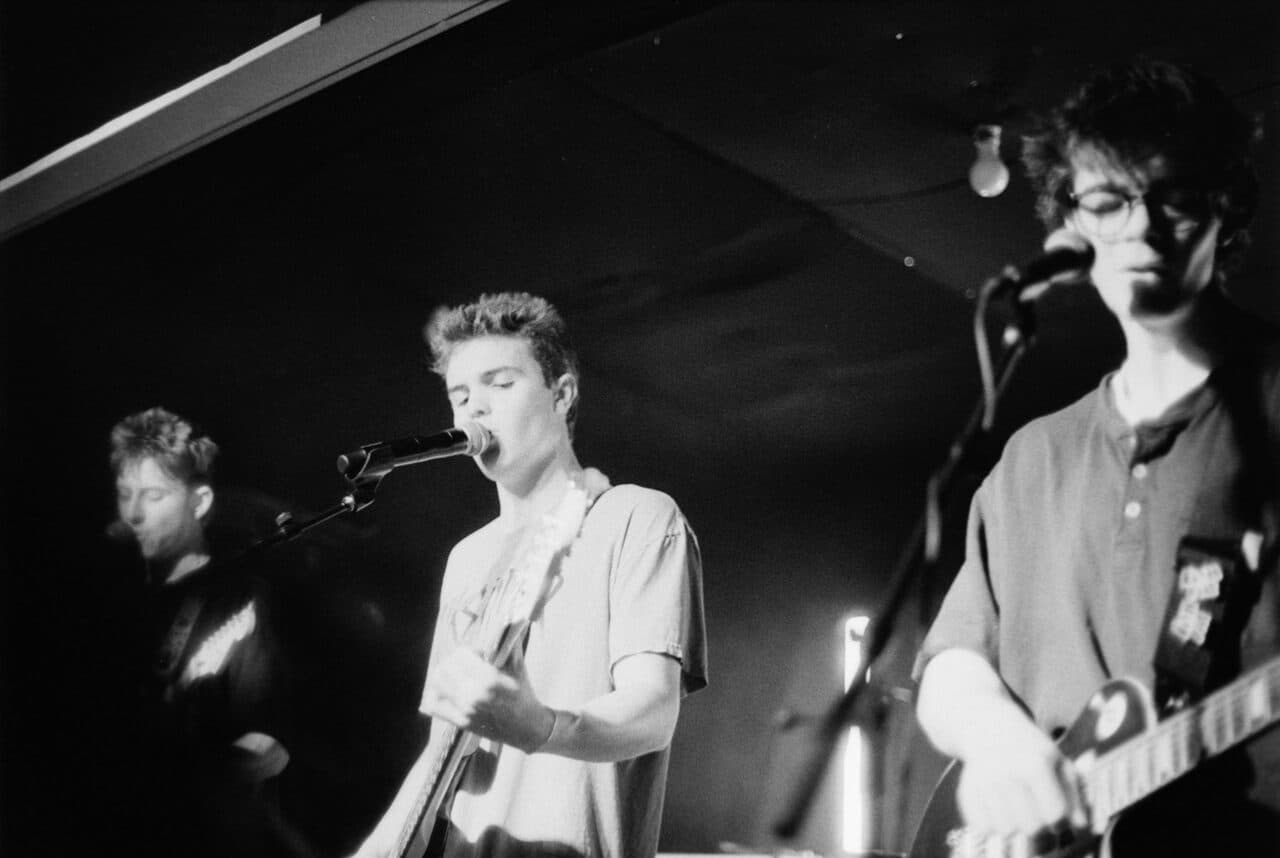 A band performing with guitars and microphones on stage